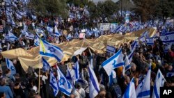 Israelis wave the national flag and carry a large copy of the Israeli Declaration of Independence to protest plans by the government to overhaul the judicial system outside the Knesset, Israel's parliament, in Jerusalem, Feb. 20, 2023. 
