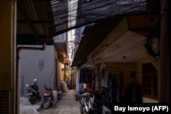 Seorang pria berjalan di gang sempit depan kediamannya di Jakarta pada 18 Mei 2022. (Foto: AFP/Bay Ismoyo)