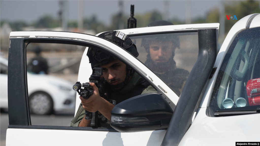 Un soldado de las Fuerzas de Defensa de Israel apunta con su fusil mientras otro observa en guardia, en uno de los bloqueos que mantienen activos en las carreteras de acceso a áreas cercanas a la Franja de Gaza, durante el conflicto con Hamás, el 11 de octubre de 2023.&nbsp;