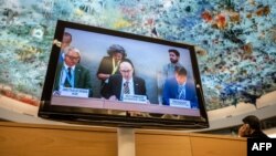 FILE: U.N. High Commissioner for Human Rights Volker Turk, center, is seen on a TV monitor speaking during a session of the 52nd U.N. Human Rights Council, in Geneva, on March 6, 2023. 