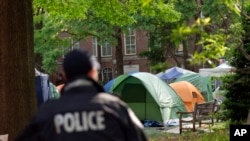 A George Washington University police officer scans the area as students demonstrate on campus during a pro-Palestinian protest against the Israel-Hamas war, April 26, 2024, in Washington. 