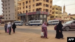 Para perempuan berjalan di sepanjang jalan di selatan Khartoum pada 24 April 2023. Gencatan senjata tiga hari antara pihak-pihak yang berperang di Sudan mulai berlaku pada Selasa. (Foto: AFP)