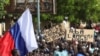 Demonstrators hold a Russian flag and banners during a rally in support of coup soldiers, in Niamey, Niger, July 30, 2023. The signs read "Down with France and its allies" and "Down with imperialism." 