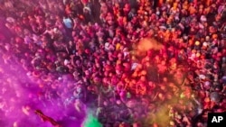 FILE - People celebrate with bright colors for Lathmar Holi at Nandagram temple in Nandgoan village, 115 kilometers (70 miles) south of New Delhi, India, March 19, 2024. (AP Photo/Rajesh Kumar Singh)