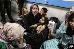 Palestinians wounded at Ahli Arab Hospital sit at al-Shifa Hospital in Gaza City, Gaza Strip, Oct. 17, 2023. The Hamas-run Health Ministry says an Israeli airstrike caused an explosion, but the Israeli military says it was a misfired Palestinian rocket.