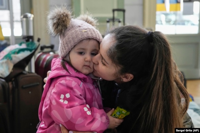 FILE - A refugee from the Ukrainian city of Mykolaiv, Anastasia Marunich, kisses her daughter Maria after fleeing the war from neighbouring Ukraine at a railway station in Przemysl, Poland, on Thursday, March 24, 2022. (AP Photo/Sergei Grits)