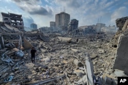 Warga Palestina berjalan melewati puing-puing bangunan yang hancur akibat serangan udara Israel di Kota Gaza, 10 Oktober 2023.
