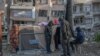 Sejumlah warga yang tedampak gempa dahsyat di Turki dan Suriah berdiri dekat tenda pengungsian yang didirikan dekat gedung yang roboh di Hatay, Turki, 15 Februari 2023. (Foto: Bulent Kilic/AFP)