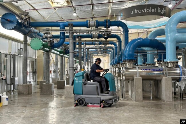 A worker cleans an ultraviolet light disinfection system as part of a water purification process at the Silicon Valley Advance Purification Center in San Jose, California, Dec. 13, 2023.