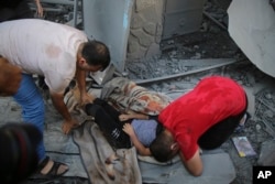 Palestinians mourn over the body of a child killed in an Israeli airstrike on the Haboush family building in Gaza City, Gaza Strip, Oct. 18, 2023.