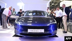 Visitors inspect a Tesla model 3 car on display at the International Motor Show (IAA) in Munich, southern Germany, Sept. 4, 2023.