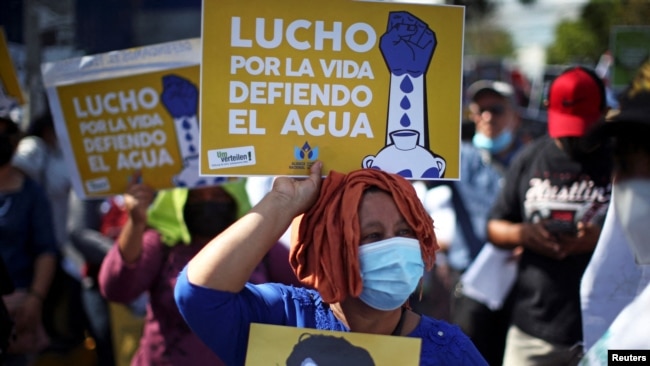 Una mujer sostiene un cartel que dice: "Lucho por la vida, defiendo el agua" durante una protesta para conmemorar el día Mundial del Agua, en San Salvador, el 22 de marzo de 2022.