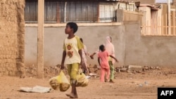 FILE - A child carries bags with bread as he walks in a street in Khartoum, Sudan, on June 20, 2023. 