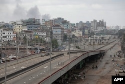 Asap mengepul dari belakang lingkungan pinggiran selatan Dhaka saat bentrokan meletus antara polisi dan pengunjuk rasa anti-kuota di Dhaka, Bangladesh, 21 Juli 2024. (Foto: AFP)