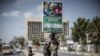 FILE - Supporters of Zambian President elect for the opposition party United Party for National Development (UPND) Hakainde Hichilema remove a poster of the former president Edgar Lungu from a pole in Lusaka, Aug. 16, 2021. 
