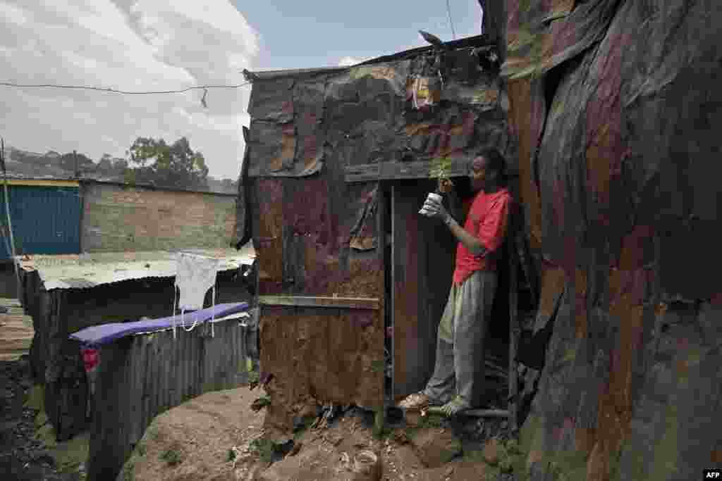 An artisanal carpenter checks on his avocado tree seedling during a break from work at his roadside workshop in the informal settlement of Mathare slum in Nairobi. 