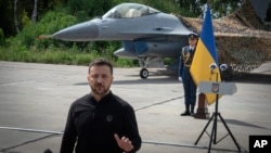 El presidente de Ucrania, Volodymyr Zelenskyy, responde preguntas de los medios de comunicación frente a un avión de combate F-16 en un lugar no revelado en Ucrania, el 4 de agosto de 2024.