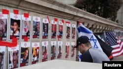 Лице се моли пред фотографиите на заложниците објавени на кампусот во близина на кампот каде што студентите протестираат за поддршка на Палестинците на Универзитетот Колумбија во Њујорк, 24 април 2024 година