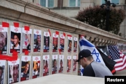 A person prays in front of photos of hostages taken captive from Israel on October 7. The fliers are near an encampment at Columbia University in New York, one of many U.S. campuses where students are protesting to show support for Palestinians, April 24, 2024.