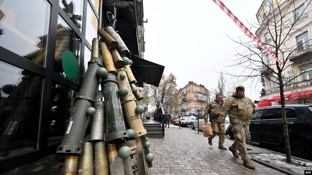 Ukrainian servicemen walk past a symbolic Christmas tree made from spent shells casing and other spent ammunition erected outside a cafe in the center of Kyiv, Dec. 18, 2023. U.S. President Joe Biden has asked Congress to approve $60 billion more in aid for Ukraine.