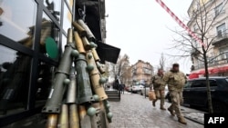 Ukrainian servicemen walk past a symbolic Christmas tree made from spent shells casing and other spent ammunition erected outside a cafe in the center of Kyiv, Dec. 18, 2023. U.S. President Joe Biden has asked Congress to approve $60 billion more in aid for Ukraine.