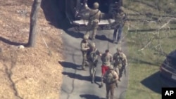 This image made from video provided by WCVB-TV shows Jack Teixeira, in T-shirt and shorts, being taken into custody by armed tactical agents on April 13, 2023, in Dighton, Mass.