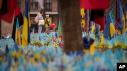 Un niño sostiene un globo mientras mira un monumento a los soldados que murieron en la guerra en Kiev, Ucrania, el jueves 14 de marzo de 2024.