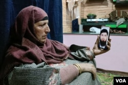 Raja Bano of Kashmir displays a picture of his son Aazad Yusuf Kumar on a phone. Kumar was promised a hotel job in the UAE, but the recruiting agent sent him to Russia, where he was forced to join the army, his family insists. (Yasir Khanday for VOA)