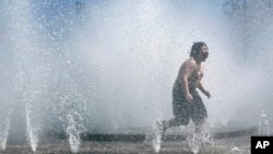 A child plays in a fountain to cool off in Portland, Oregon, May 12, 2023. An early May heat wave this weekend could surpass daily records in parts of the Pacific Northwest and worsen wildfires already burning in western Canada.