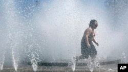 Un niño juega en una fuente para refrescarse en el centro de Portland, Oregón, EEUU, el 12 de mayo de 2023.