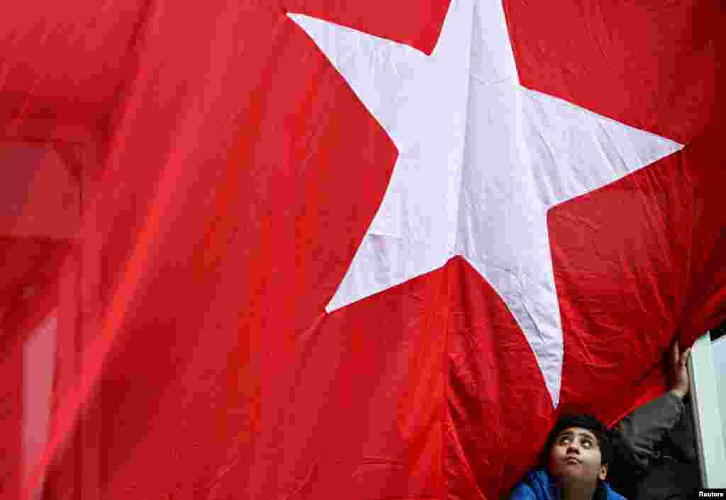 A boy looks out a window of a building where a Turkish flag hangs ahead of the presidential and parliamentary elections, in Istanbul, Turkey.