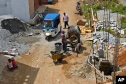 Preethi, mengendarai becak listrik beratap biru melewati lokasi konstruksi di Bengaluru, India, Rabu, 12 Juli 2023. (AP/Aijaz Rahi)