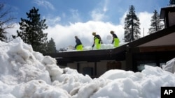 FILE - Members of a Cal Fire crew clear snow off the roof of the town's post office after a series of storms on March 8, 2023, in Crestline, Calif.