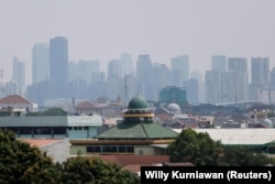 Masjid terlihat di kawasan pemukiman, dengan latar belakang kabut asap menutupi gedung-gedung bertingkat, Jakarta, 9 Agustus 2023. (Foto: REUTERS/Willy Kurniawan)