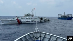 FILE - A Chinese coast guard ship, left, with a Chinese militia vessel, right, blocks Philippine coast guard ship BRP Sindangan as it tried to head towards Second Thomas Shoal at the disputed South China Sea during rotation and resupply mission on Oct. 4, 2023. 