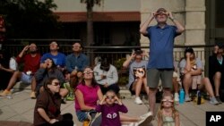 Viewers use special glasses to watch as the moon moves in front of the sun during an annular solar eclipse, or ring of fire, Oct. 14, 2023, from San Antonio.