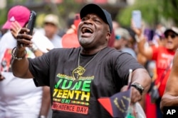 FILE - Tyrone Stroman, of Washington, wears a T-shirt that reads "Juneteenth is my Independence Day" as he dances to an Earth, Wind, and Fire Tribute Band during a Juneteenth celebration at Black Lives Matter Plaza in Washington, Monday, June 19, 2023. (AP Photo/Andrew Harnik)