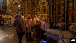 Orthodox Christian worshipers light candles during an Easter Sunday service in Kyiv, Sunday, Apr. 16, 2023.