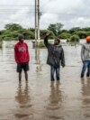 FILE - Residents inspect a road heavily affected by floods following torrential rains in Kitengela, on May 1, 2024. 