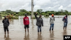 FILE - Residents inspect a road heavily affected by floods following torrential rains in Kitengela, on May 1, 2024. 