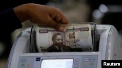 FILE — A Kenya Commercial Bank, KCB, Mtaani agent counts shilling notes on a money counting machine as she serves a client inside in the banking hall at the Kencom branch in Nairobi, on July 10, 2018. 