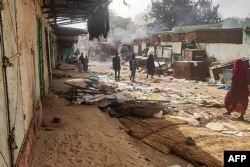 FILE - People walk among scattered objects in the market of El Geneina, the capital of West Darfur, on April 29, 2023.