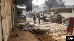 FILE - People walk among scattered objects in the market of El Geneina, the capital of West Darfur, on April 29, 2023. Reports say people fleeing the city and surrounding area are getting shot down by combatants. 
