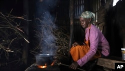 FILE - Jane Muthoni, 65, cooks using firewood at her home in Kiambu, Kenya, May 21, 2024. 