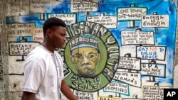 A man walks past a mural, painted for a previous election and showing incumbent President Muhammadu Buhari, in Lagos, Nigeria, Feb. 24, 2023. 