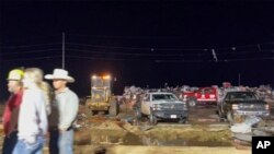 In this image made from video provided by KAMC/KLBK, people stand near debris in Matador, Texas, June 21, 2023, following storms went through the area. (KAMC/KLBK via AP)