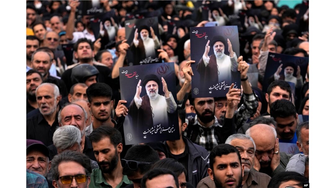 Orang-orang memegang poster Presiden Ebrahim Raisi saat upacara berkabung untuknya di alun-alun Vali-e-Asr di pusat Kota Teheran, Iran, Senin, 20 Mei 2024. (Foto: AP)