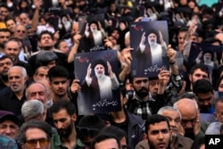 Orang-orang memegang poster Presiden Ebrahim Raisi saat upacara berkabung untuknya di alun-alun Vali-e-Asr di pusat Kota Teheran, Iran, Senin, 20 Mei 2024. (Foto: AP)