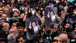 Sejumlah warga memegang poster mendiang Presiden Iran Ebrahim Raisi saat berkumpul di pusat kota Tehera, Iran, untuk mengenang kepergian sang presiden, pada 20 Mei 2024. (Foto: AP/Vahid Salemi)