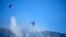 A helicopter drops water over a wildfire atop Mount Parnitha, in northwestern Athens, Greece, Aug. 24, 2023.